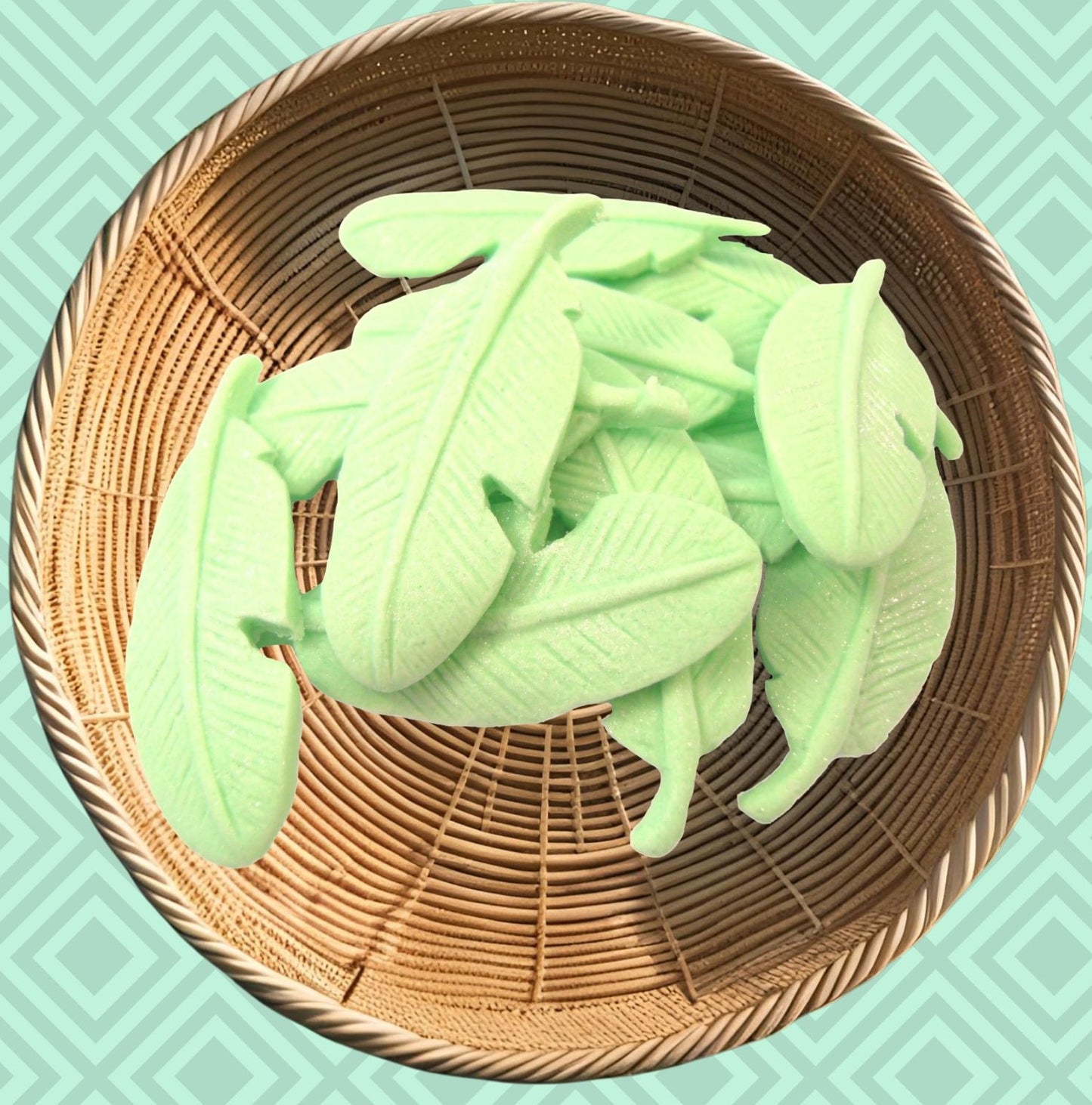 Green glittered feathers edible decorations on a woven basket against a teal background