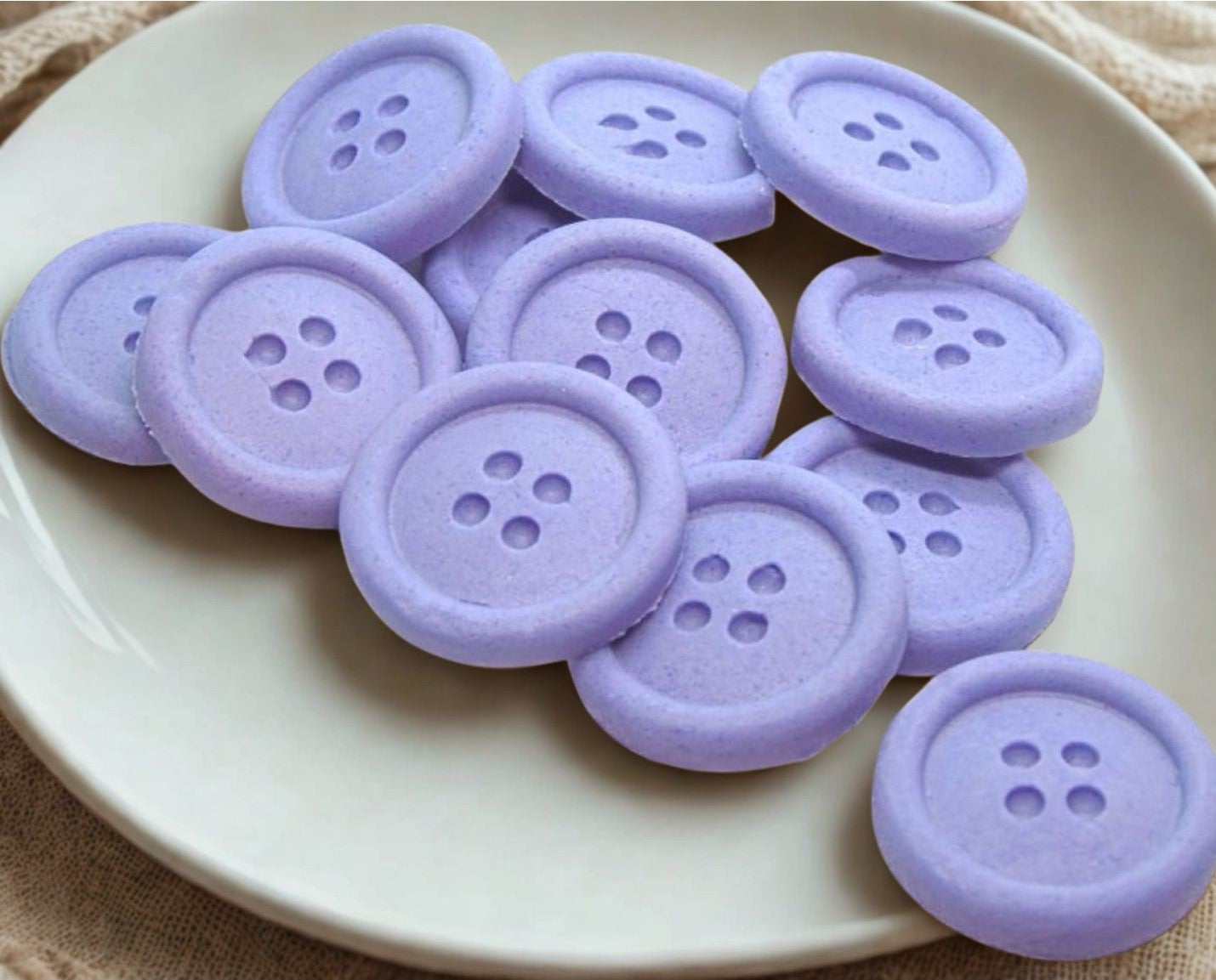 Purple edible buttons on a white plate with a white cloth background