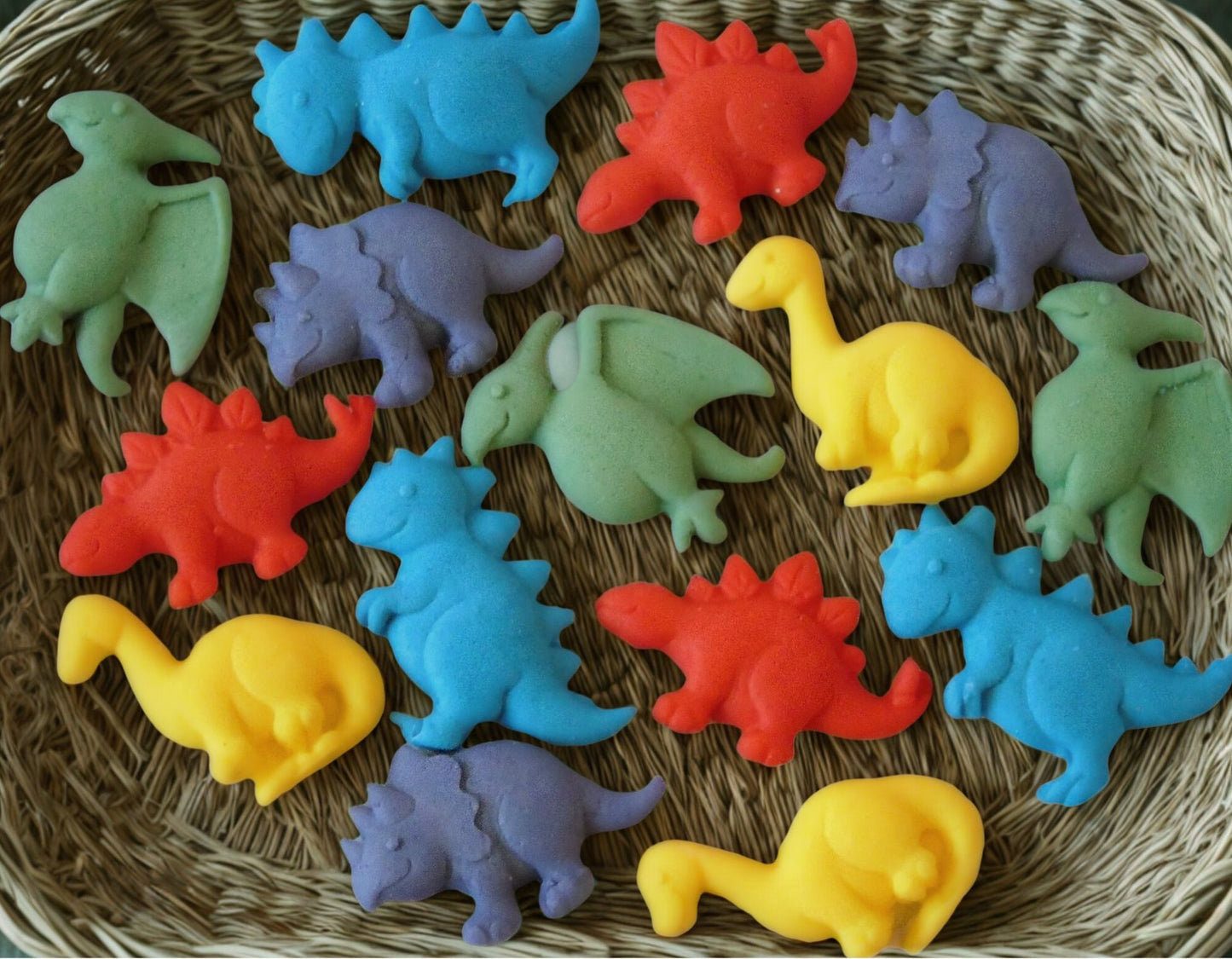 15 Colorful dinosaur cupcake toppers laying on a woven surface