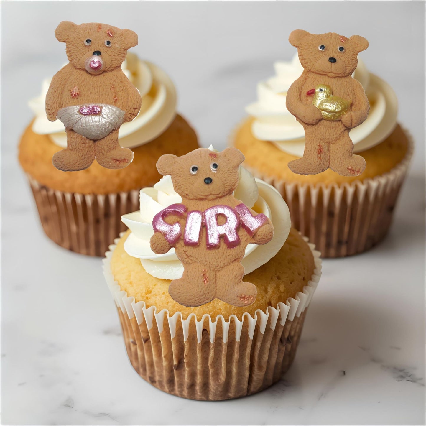 Cupcakes with brown teddy bear toppers on a marble surface