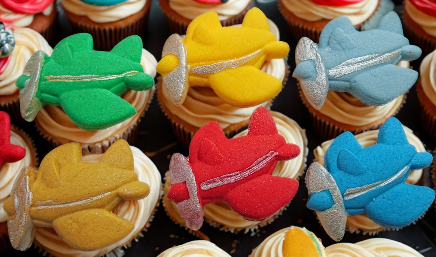 Cupcakes with colorful airplane-shaped decorations on a black background