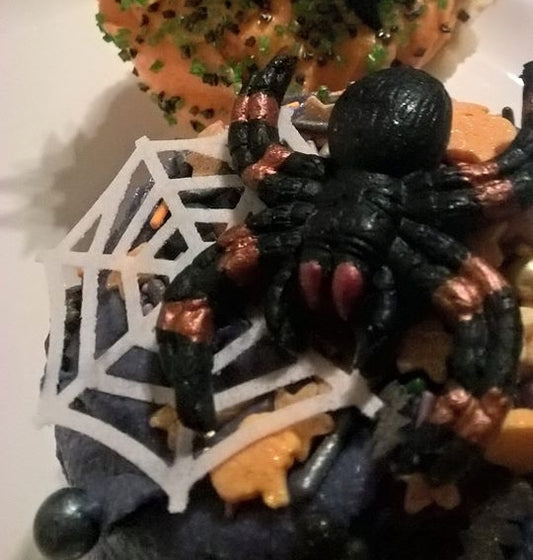 Black edible spider on a decorative cupcake with a spider web