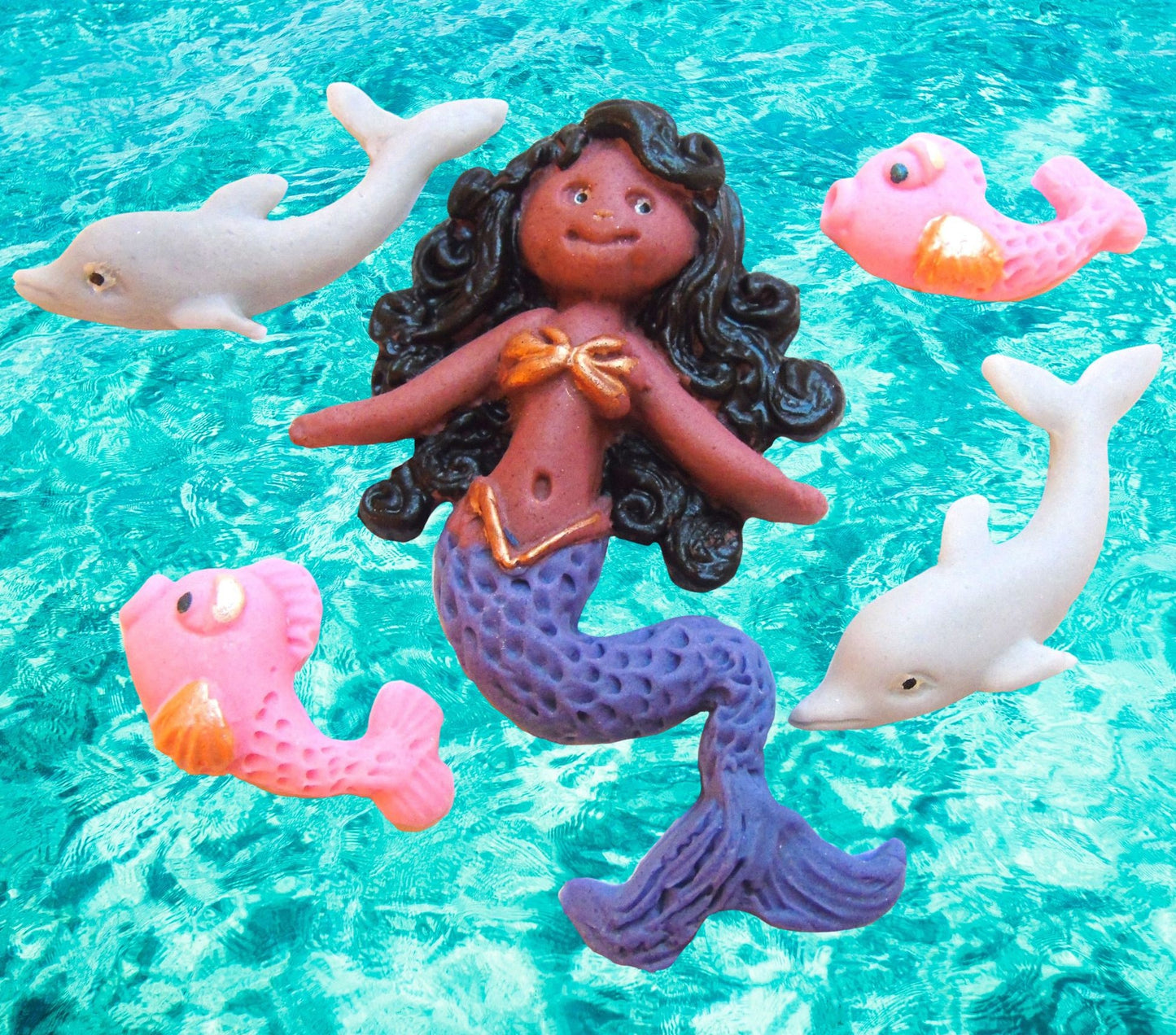 mermaid figurine with dolphins and fish cake topper decorations on a blue water background