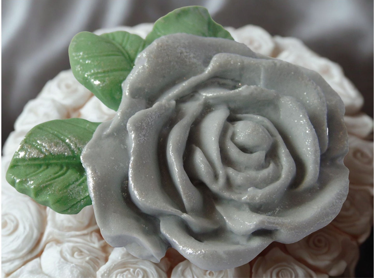 Large silver rose with green leaves on a cake