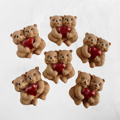 Small brown teddy bears holding red hearts on a white background