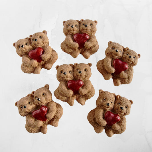 Small brown teddy bears holding red hearts on a white background