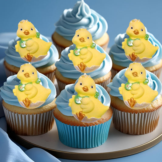 Cupcakes with blue frosting and yellow duck decorations on a tray.