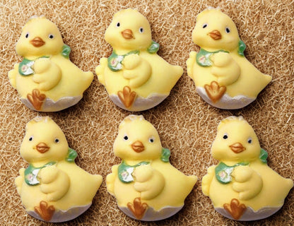 Six yellow chick figurines with green bibs on a textured brown background