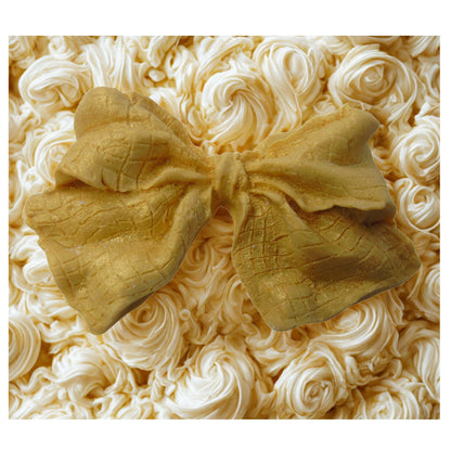 large gold glittered edible bow on a white cake