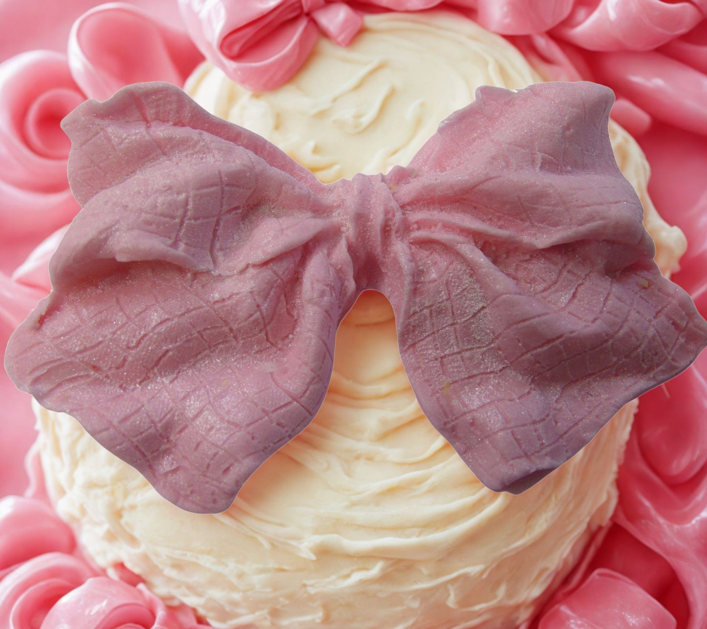 large pink glittered edible bow on a white cake