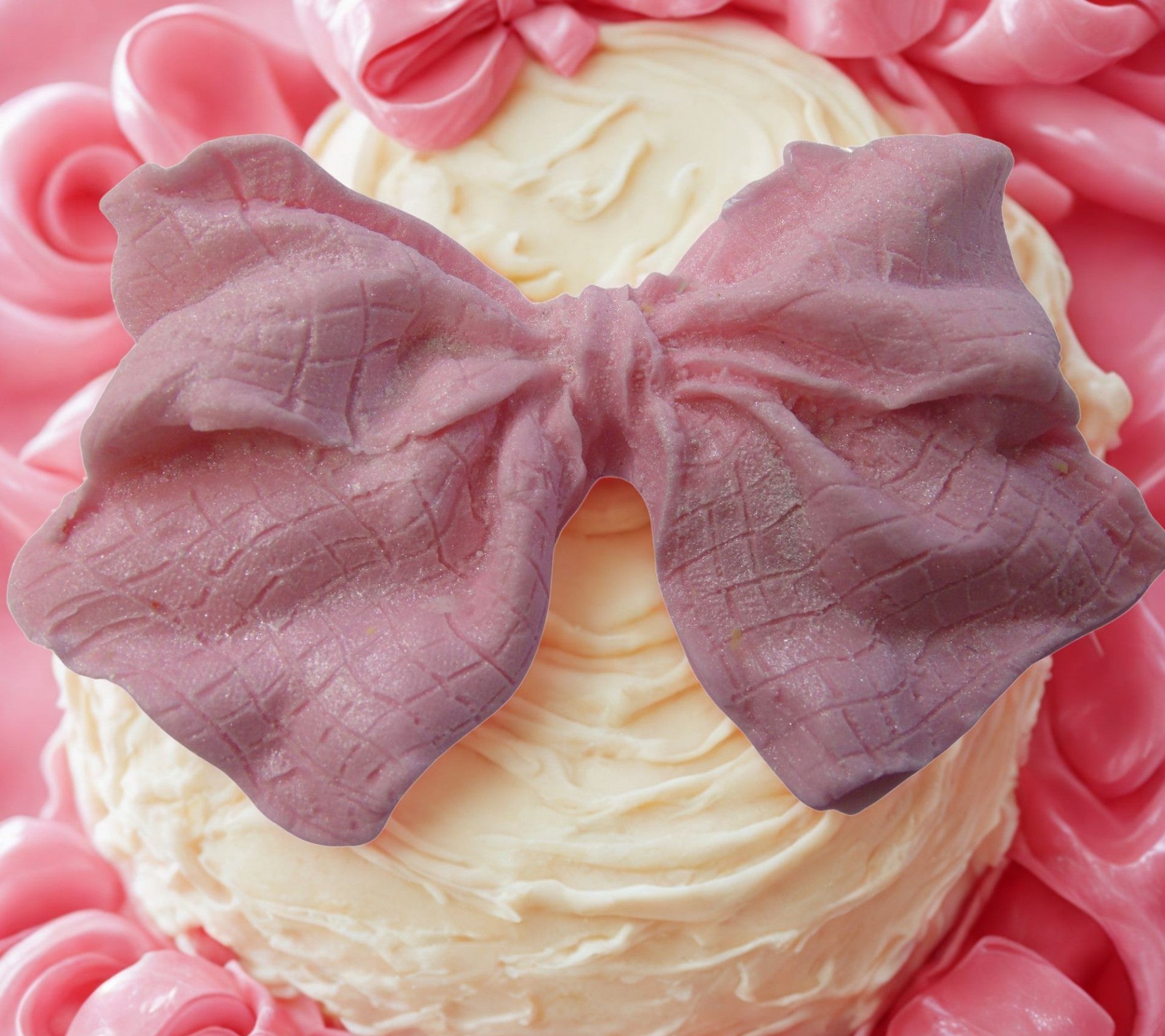 large pink glittered edible bow on a white cake