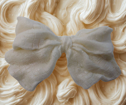 large silver glittered edible bow on a white cake